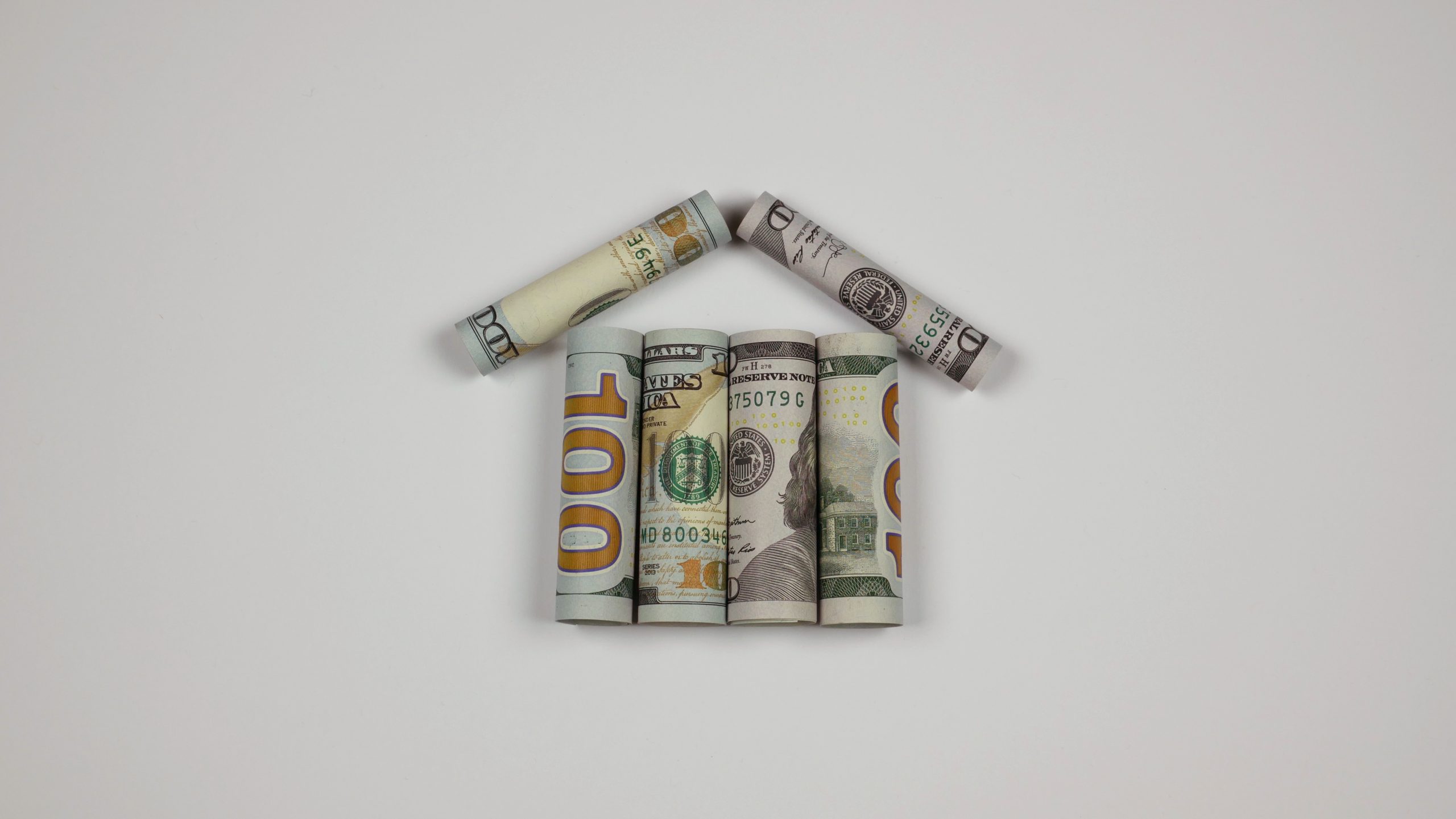 Rolled dollar bills forming a small home shape